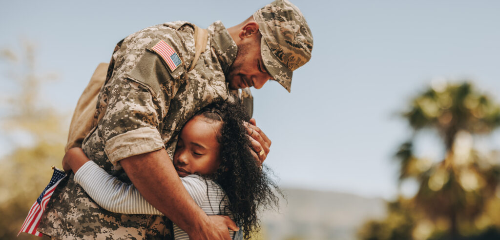 Affectionate military reunion between father and daughter. Emotional military dad embracing his daughter on his homecoming. Army soldier receiving a warm welcome from his child after deployment.